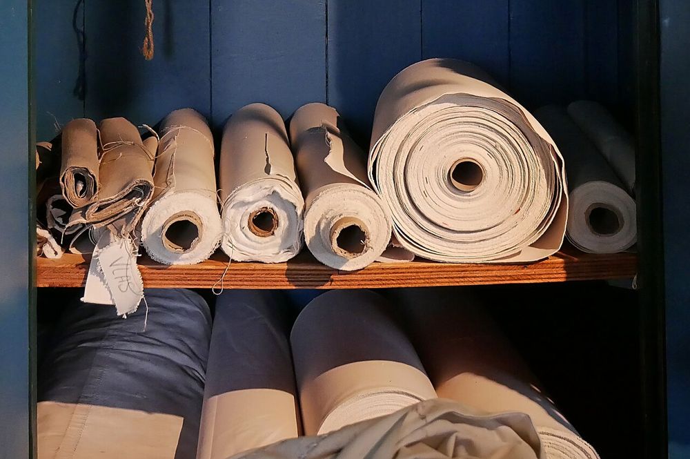 Rouleaux de toile à voile rangés sur une étagère d'atelier